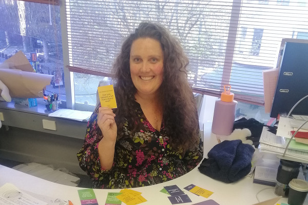Whitecliffe staff member holding up a conversation card used to help improve professional conversations